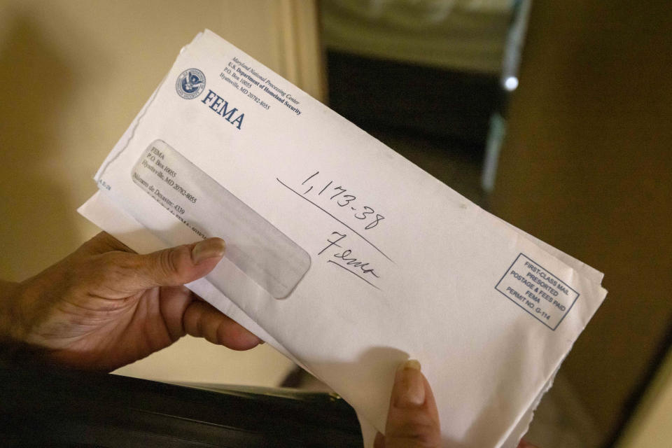 Virmisa Rivera holds an envelope with the amount of money she was given to repair her hurricane-damaged home in Loiza, Puerto Rico, Thursday, Sept. 15, 2022. She said FEMA also gave her $1,600 to rent a house while they repaired her roof, but no crews came by. The government said it would move her to a new home in another neighborhood since they can’t repair hers because it’s in a flood zone. (AP Photo/Alejandro Granadillo)