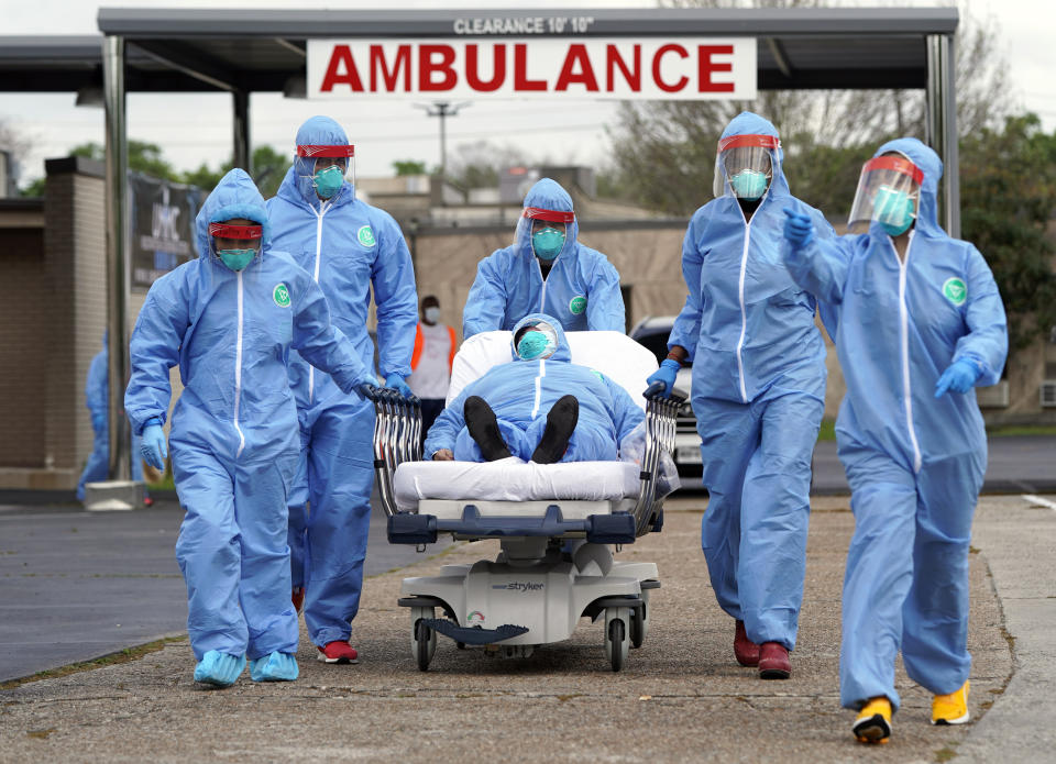 In Houston, a patient is taken by stretcher into the United Memorial Medical Center after going through testing for COVID-19. Cars were lined up for more than two miles, as people awaited coronavirus tests at a drive-thru testing station. (AP Photo/David J. Phillip) 