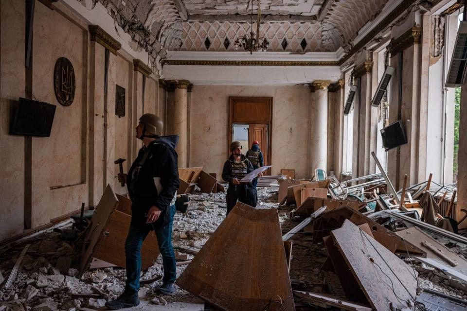 Engineers examine a damaged official building in Kharkiv on Monday after it was bombed by Russian forces (AFP via Getty Images)