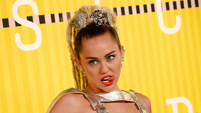 Miley Cyrus jokes that she may be wearing the bare minimum amount of clothes on TV (again!), but we're not so sure she's kidding. Cyrus will pull double duty as host and musical guest on <em>Saturday Night Live</em>'s season 41 premiere on Saturday, Oct. 3, and in new promos, Cyrus says she'll be doing her jobs "with or without clothes, we're not sure yet." <strong> WATCH: Miley Cyrus Reportedly Hooking Up With Dane Cook</strong> In typical Miley fashion, the 22-year-old sported a totally out there outfit -- a multi-colored metallic dress with oversized iridescent mushroom earrings -- for the promos, which also featured <em>SNL</em> regular Taran Killam. "You know Miley, I expected you to wear something crazier," Killam says in one of the promos. "What? I don't do that all the time," she replies. Cyrus then gives Killam a sneak peak of an outfit she has in mind, which is basically a black string with two pieces of shiny gold fabric. "So no pants," he asks. <strong> WATCH: Miley Cyrus Gets Dissed By Another Rapper</strong> "What are pants?" Cyrus jokes, again. Looks like we'll have to wait until the weekend to see if she actually pulls off the look. In the meantime, watch the video below to see all of the funny promos from Cyrus and Killam. The singer took to Instagram to share a photo of the two on the <em>SNL </em>set on Tuesday. "F-- yeah @nbcsnl," the singer captioned the photo. "Feels goooood to be back afta 40." "My mood exactly about SNL dis weeeek!," she wrote on another pic posted the same day. This isn't the first time we've seen Cyrus hosting <em>SNL</em>. The "Wrecking Ball" singer led <em>SNL</em> in March 2011 and again in October 2013. Most recently, Cyrus hosted the MTV Video Music Awards late last month in Los Angeles. Watch the video below to see her not-so-shocking on-camera nip-slip, plus six other VMA surprises.