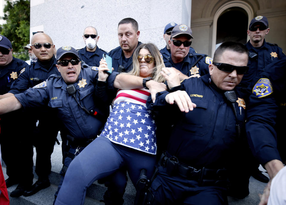 A protester is detained by California Highway Patrol officers during a demonstration against Gov. Gavin Newsom's stay-at-home orders due to the coronavirus pandemic, at the Capitol in Sacramento, Calif., Friday, May 1, 2020. Several people were taken into custody during the protest calling for Newsom to ease the restrictions and allow people return to work. (AP Photo/Rich Pedroncelli)