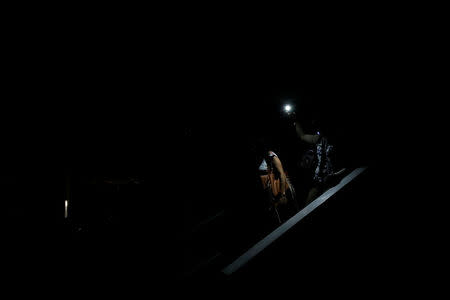 People use light from a phone while they walk on the staircase of a parking garage during a blackout in Caracas, Venezuela February 6, 2018. REUTERS/Carlos Garcia Rawlins