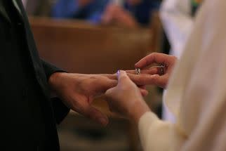 woman placing wedding band on husband's finger marriage vows