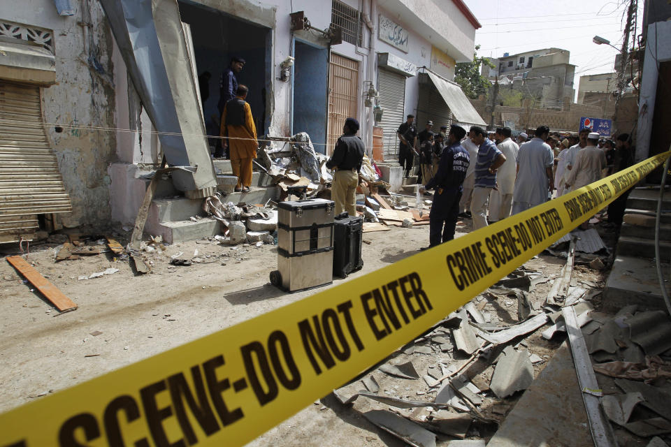 Pakistani security officials inspect the site of a bomb attack in Karachi Thursday, April 24, 2014. A Pakistani official says a bombing in the country's south targeted a police officer known for his anti-militant campaigns, killing him and his two friends. (AP Photo/Fareed Khan)