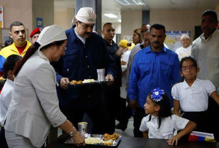 Venezuela's President Nicolas Maduro (C) serves lunch during an event related to the beginning of classes at a school in Caracas, Venezuela September 18, 2017. Miraflores Palace/Handout via REUTERS