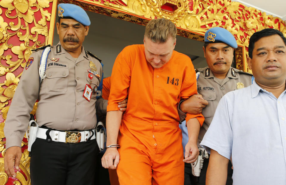 Police officers escort Australian national David van Iersel, center, to a press conference at the regional police headquarters in Denpasar, Bali, Indonesia Tuesday, July 23, 2019. Indonesian police say two Australian men have been arrested with cocaine on Bali. (AP Photo/Firdia Lisnawati)