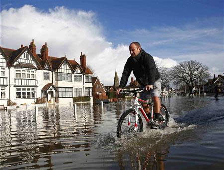 A resident cycles through deep water after the river Thames flooded the village of Datchet, southern England February 10, 2014. REUTERS/Eddie Keogh