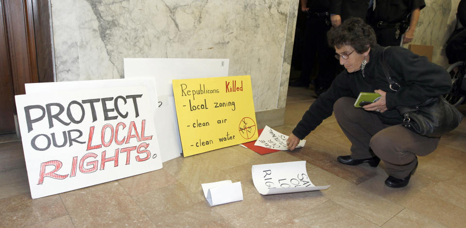 A woman gathers a pile of signs as she leaves the the Pennsylvania state Supreme Courtroom in Pittsburgh where the court was hearing arguments from seven municipalities challenging portions of a new law that regulates natural gas exploration on Wednesday, Oct. 17, 2012. (AP Photo/Keith Srakocic)