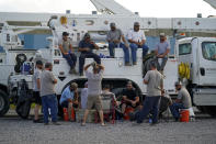 Electrical workers congregate in the evening after parking their trucks after a day's work at a tent city in Amelia, La., Thursday, Sept. 16, 2021. In the wake of hurricanes, one of the most common and comforting sites is the thousands of electric workers who flow into a battered region when the winds die down to restore power and a sense of normalcy. (AP Photo/Gerald Herbert)