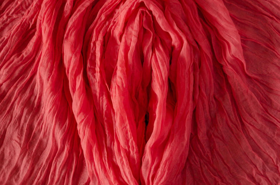 Rippling, pleated fabric arranged in layers, resembling petals or waves, creating a textured pattern