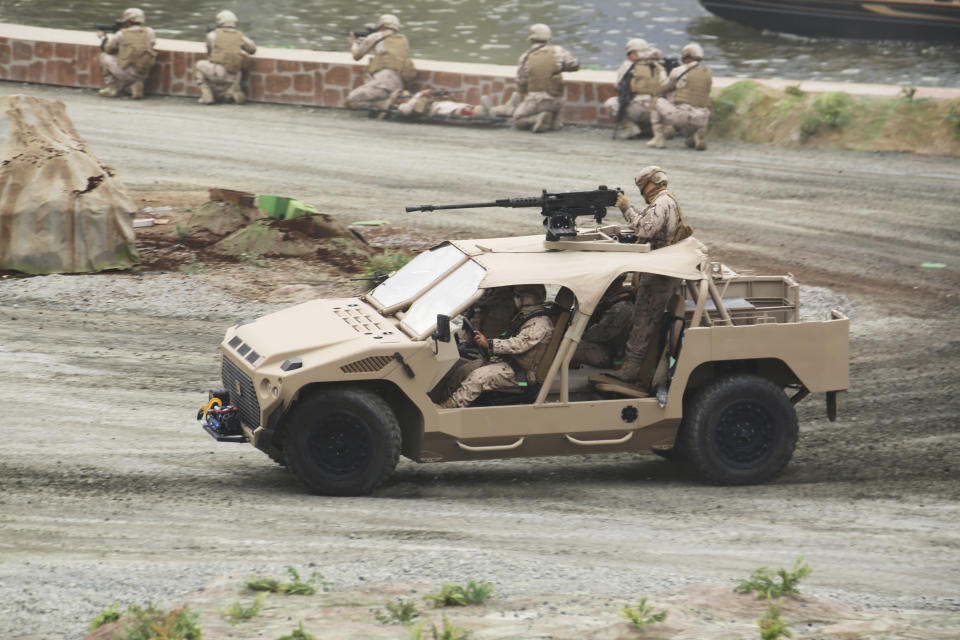 Soldiers in an attack vehicle drive by other troops during a military demonstration at the International Defense Exhibition and Conference in Abu Dhabi, United Arab Emirates, Sunday, Feb. 17, 2019. The biennial arms show in Abu Dhabi comes as the United Arab Emirates faces increasing criticism for its role in the yearlong war in Yemen. (AP Photo/Jon Gambrell)