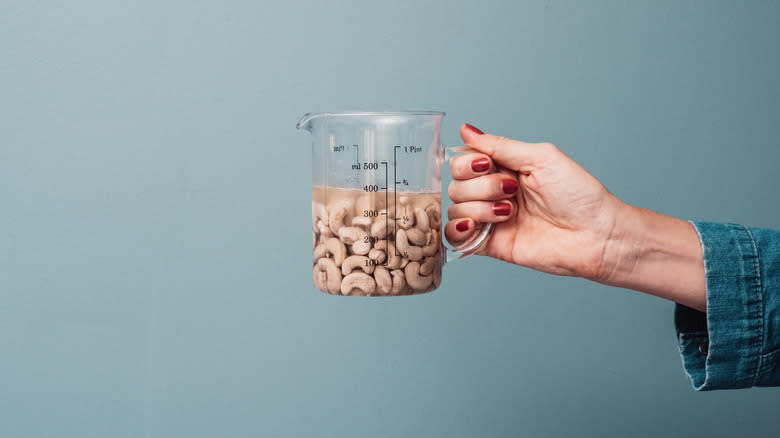 Hand holding cashews in liquid