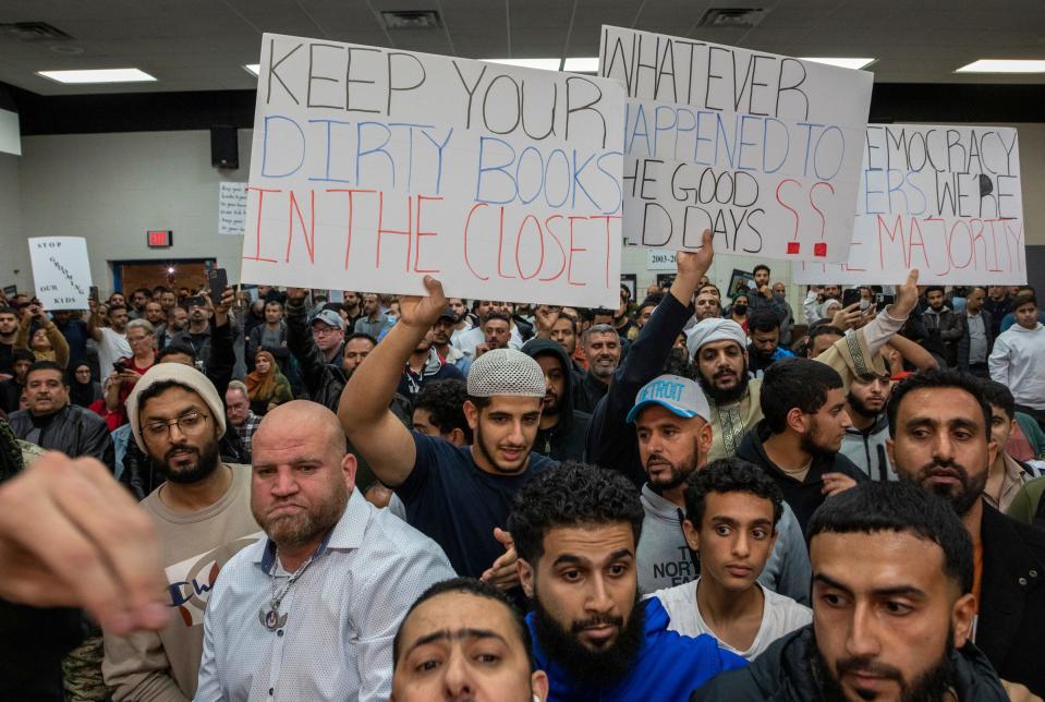 Community members hold signs protesting against particular educational material inside the Dearborn Schools Administrative Service Center during the Dearborn Board of Education meeting in Dearborn on Oct. 10, 2022.