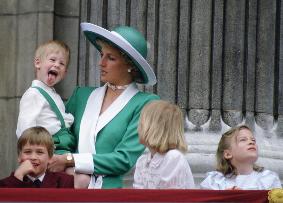 A young Prince Harry sticking his tongue out in the arms of his mother, Princess Diana, at Trooping The Colour, with  Prince William, Lady Gabriella Windsor And Lady Rose Windsor, watching from the balcony of Buckingham Palace.  / Credit: Tim Graham Photo Library via Getty Images