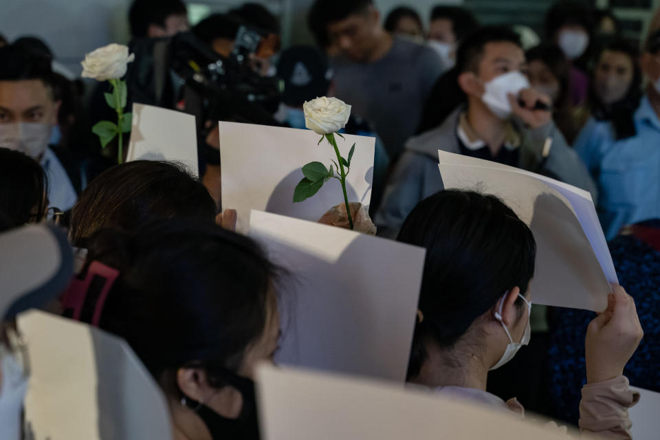 People hold up sheets of blank paper in protest of COVID restriction in China as police set up cordons during a vigil in the central district on Nov. 28, 2022, in Hong Kong.