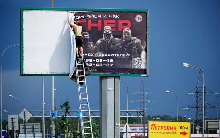 A man takes down the poster with writing reading &quot;Join us at Wagner&quot;, which is associated with the owner of the Wagner private military contractor, Yevgeny Prigozhin, is seen above a highway on the outskirts of St. Petersburg, Russia, Saturday, June 24, 2023. Russia&#39;s security services have responded to mercenary chief Prigozhin&#39;s declaration of an armed rebellion by calling for his arrest. In a sign of how seriously the Kremlin took the threat, security was heightened in Moscow, Rostov-on-Don and other regions. (AP Photo)