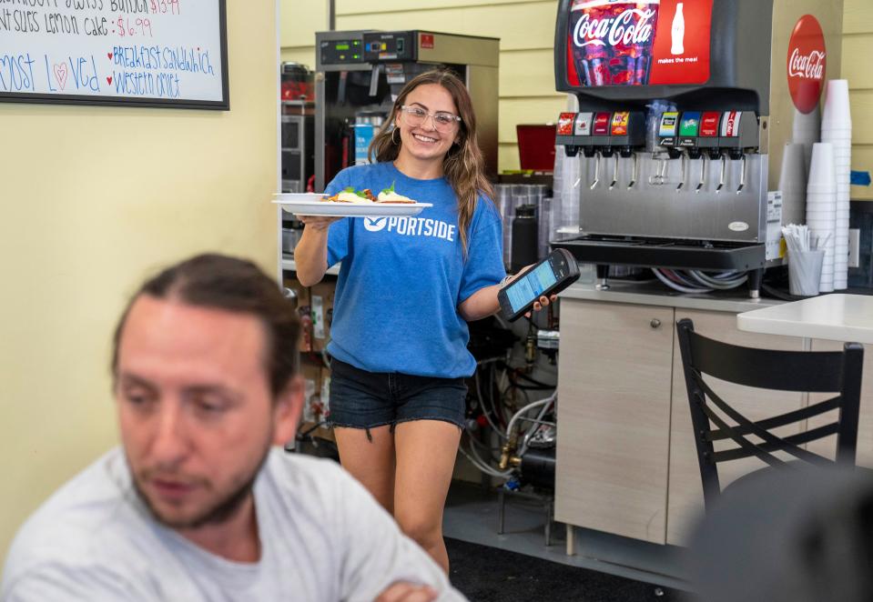 Waitress Caitlin Williams carries breakfast to a customer dining at Portside Breakfast & Lunch restaurant in West Palm Beach on November 17, 2022.