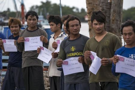 Migrant workers hold up their identity cards at a port in Samut Songkhram province, Thailand, July 1, 2015. REUTERS/Athit Perawongmetha