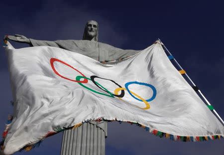 The Olympic Flag flies in front of "Christ the Redeemer" statue during a blessing ceremony in Rio de Janeiro August 19, 2012. REUTERS/Ricardo Moraes
