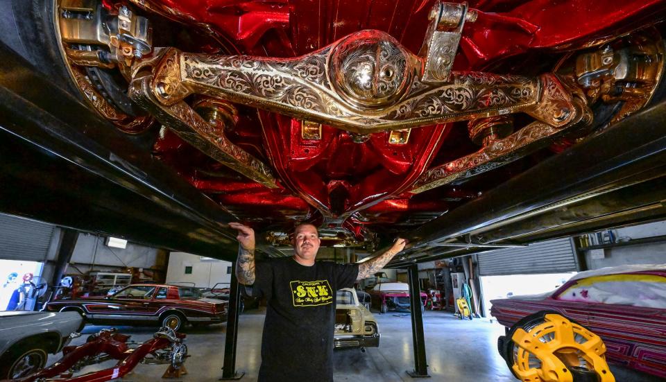 Steven Burk poses under a 1962 Chevy Impala with 40-50K hours of work into it- so far. Burk has been painting cars since he was 8-years-old and has been running his own custom shop, SNK Autobody & Hydraulics, for about 20 years.