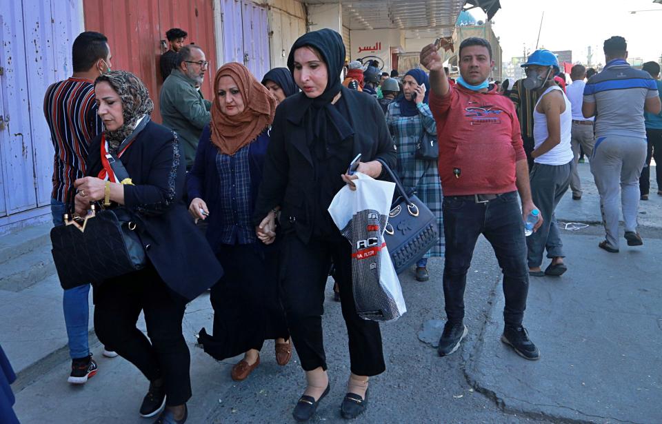 Employees of the central bank leave their workplaces in central Baghdad, Iraq, Wednesday, Nov. 6, 2019. Iraqi security forces deployed in large numbers around the bank and began evacuating employees from the building. The protesters did not appear to be heading toward the bank itself. (AP Photo/Hadi Mizban)