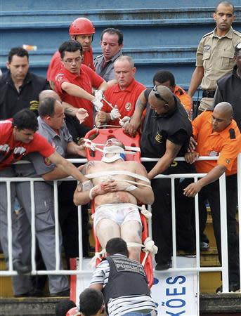 Paramedics use a stretcher to carry an injured Atletico Paranaense fan after clashes between fans of Vasco da Gama and Atletico Paranaense during their Brazilian championship match in Joinville in Santa Catarina state December 8, 2013. REUTERS/Carlos Moraes