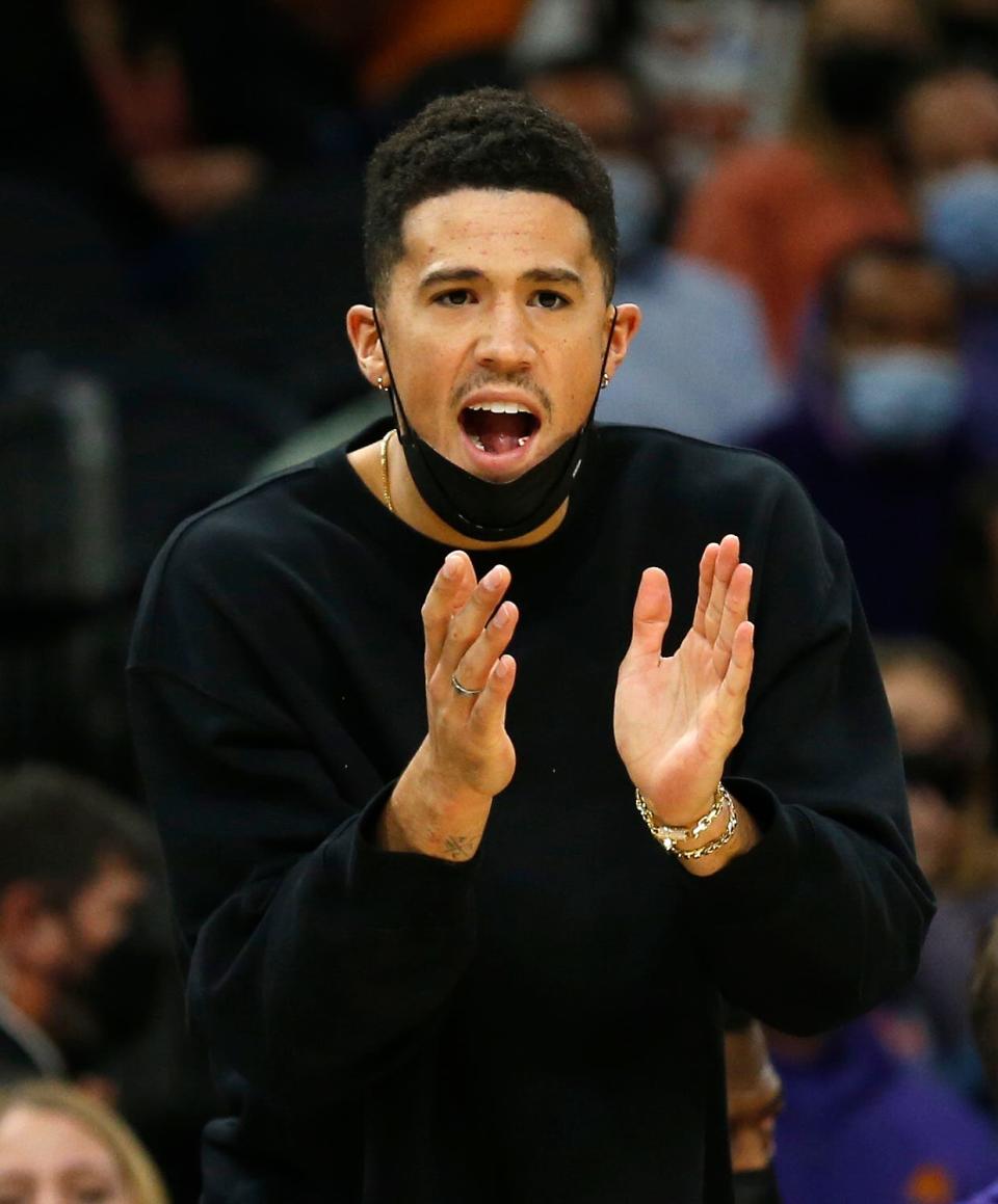 December 6, 2021; Phoenix, USA; Suns' Devin Booker cheers on the team from the bench during the second half against the Spurs at the Footprint Center. Patrick Breen-Arizona Republic