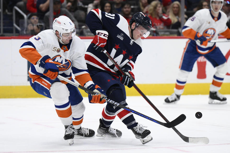 Washington Capitals center Joe Snively, right, battles for the puck against New York Islanders defenseman Adam Pelech (3) during the second period of an NHL hockey game, Monday, April 10, 2023, in Washington. (AP Photo/Nick Wass)