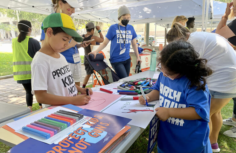 Nine-year-old Max Tretta, whose sister is a school shooting survivor, and 6-year-old Allison Salas made posters before the Los Angeles march began. (Linda Jacobson)