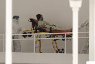 A patient infected with the new coronavirus is transferred on a stretcher at the National Hospital emergency entrance in San Salvador, El Salvador, Friday, Aug. 7, 2020. For months, the strictest measures confronting the COVID-19 pandemic in Latin America seemed to keep infections in check, in El Salvador, but a gradual reopening combined with a political stalemate has seen infections increase nearly fourfold. (AP Photo/Salvador Melendez)