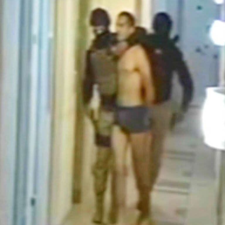 Dos de los secuestradores conducen al teniente venezolano por los pasillos de su edificio