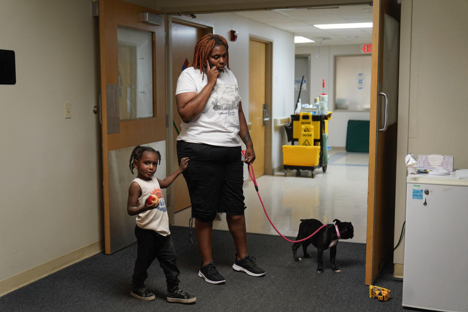 Toriana Hill talks on the phone inside a Red Cross shelter with her son Nassir Gladney, 3, and puppy Luna Wednesday, May 31, 2023, in Davenport, Iowa. Hill and her son escaped from the sixth floor after their apartment building partially collapsed Sunday afternoon. Five residents of the same building remained unaccounted for Wednesday, and authorities feared at least two of them might be stuck inside rubble that was too dangerous to search. (AP Photo/Erin Hooley)