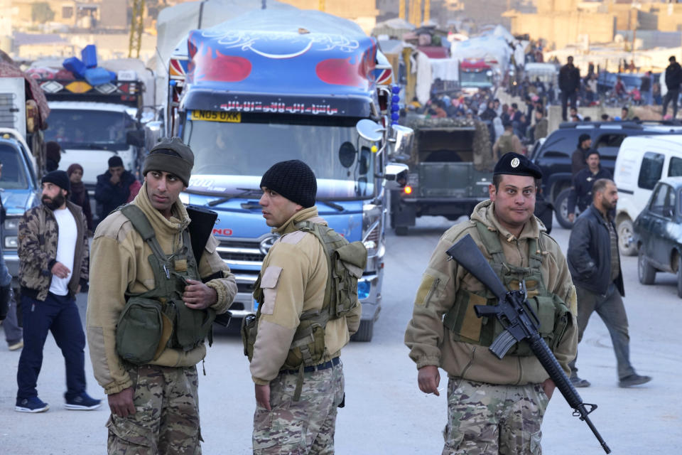 Lebanese soldiers stand in front of trucks convoy that carry Syrian refugees and their belongings, at a gathering point where they prepare to cross the border back home to Syria, in the eastern Lebanese border town of Arsal, Lebanon, Wednesday, Oct. 26, 2022. Several hundred Syrian refugees boarded a convoy of trucks laden with mattresses, water and fuel tanks, bicycles – and, in one case, a goat – Wednesday morning in the remote Lebanese mountain town of Arsal in preparation to return back across the nearby border.(AP Photo/Hussein Malla)