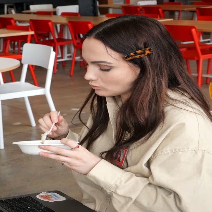 A woman eating food from a bowl.