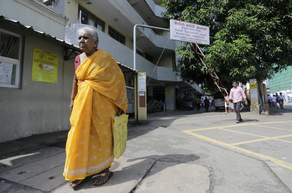 Sri Lankans walk past the National Hospital during a day long token strike launched by the members of Government Medical Officers Association in Colombo, Sri Lanka, Wednesday, Sept. 18, 2019. The trade union action is to demand the government resolve salary anomalies faced by the doctors serving at state-run hospitals. (AP Photo/Eranga Jayawardena)