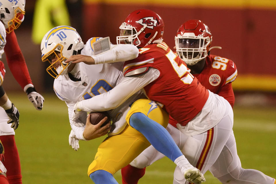 Los Angeles Chargers quarterback Justin Herbert is sacked by Kansas City Chiefs defensive end Alex Okafor, right, during the second half of an NFL football game, Sunday, Jan. 3, 2021, in Kansas City. (AP Photo/Charlie Riedel)