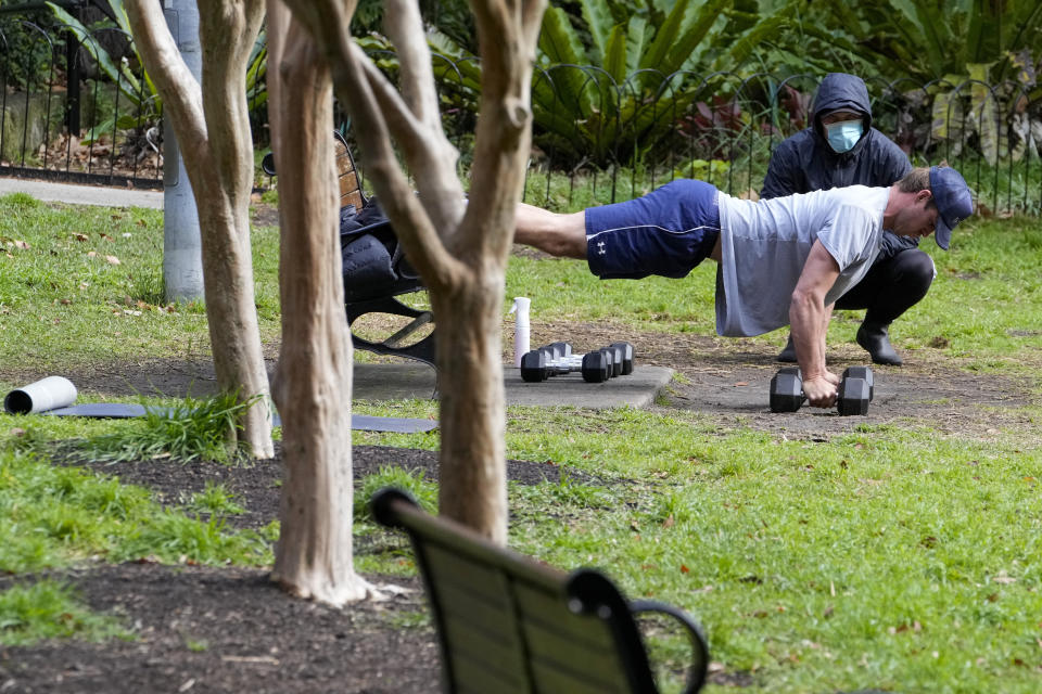 A personal trainer watches a client workout in a park in the eastern suburbs of Sydney Tuesday, Sept. 14, 2021. Personal trainers have turned a waterfront park at Sydney’s Rushcutters Bay into an outdoor gym to get around pandemic lockdown restrictions. (AP Photo/Mark Baker)