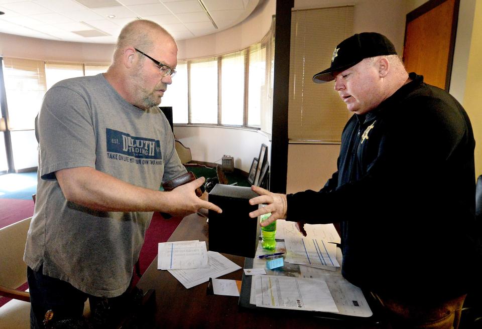 William Knuth, left, presents the box of ashes believed to be his mother's to Sangamon County Coroner Jim Allmon, Tuesday, Oct. 10, 2023.