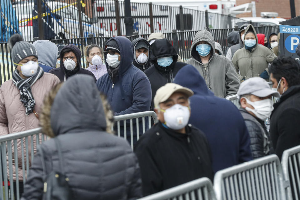 FILE - In this March 25, 2020, file photo, patients wear personal protective equipment while maintaining social distancing as they wait in line for a COVID-19 test at Elmhurst Hospital Center, in New York. As coronavirus rages out of control in other parts of the U.S., New York is offering an example after taming the nation’s deadliest outbreak this spring — but also trying to prepare in case another surge comes. (AP Photo/John Minchillo)