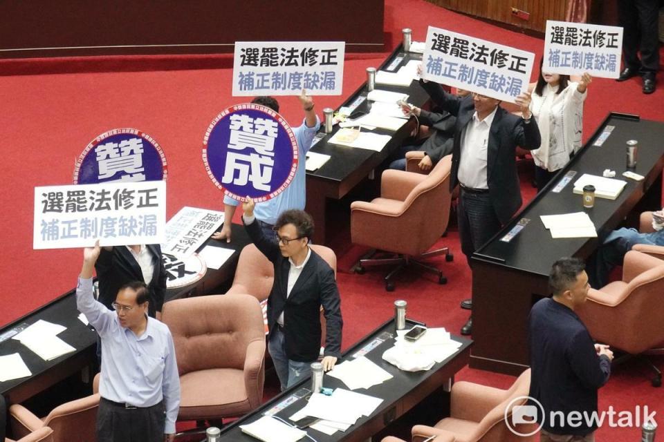 民進黨立委在立院議場舉牌反對選罷法修正草案逕付二讀，國民黨立委也舉牌反制。   圖：張良一/攝