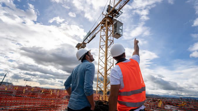 Architects looking at the view from a construction site and pointing at a crane.