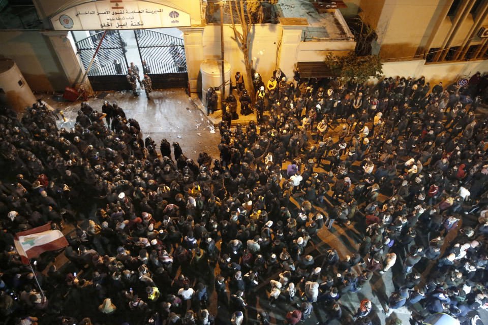 Anti-government protesters gather outside a police headquarters, as they demand the release of those taken into custody the night before, outside a police headquarter, in Beirut, Lebanon, Wednesday, Jan. 15, 2020. Lebanese security forces arrested 59 people, the police said Wednesday, following clashes overnight outside the central bank as angry protesters vented their fury against the country's ruling elite and the worsening financial crisis. (AP Photo/Hussein Malla)