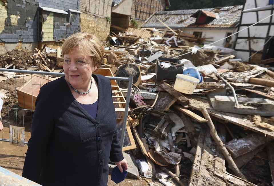 German Chancellor Angela Merkel, center, informs herself in the district of Iversheim about the situation in the flood-affected area and meet victims of the flood disaster Tuesday, July 20, 2021. (Wolfgang Rattay/Pool Photo via AP)