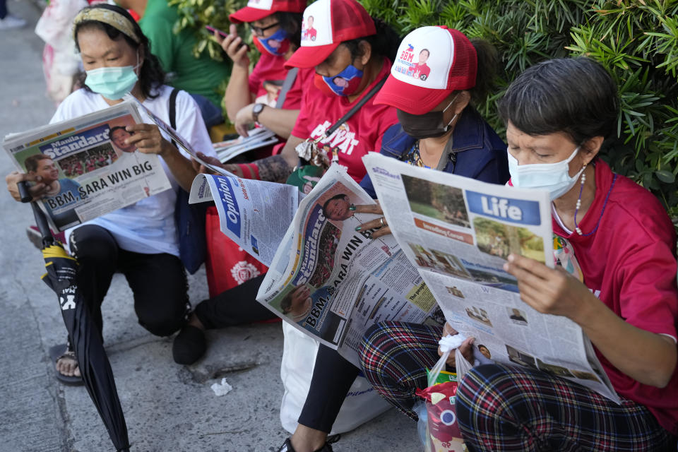 Women read newspapers showing a headline story on Ferdinand "Bongbong" Marcos Jr. and running mate Davao City Mayor Sara Duterte as they celebrate outside their headquarters in Mandaluyong, Philippines on Tuesday May 10, 2022. Marcos Jr.'s apparent landslide victory in the Philippine presidential election is giving rise to immediate concerns about a further erosion of democracy in the region, and could complicate American efforts to blunt growing Chinese influence and power in the Pacific. (AP Photo/Aaron Favila)
