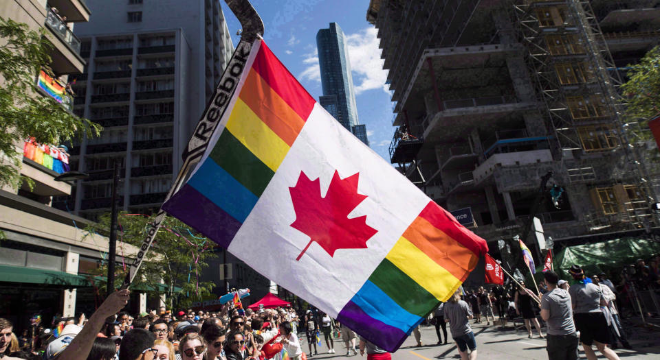 A man holds a flag on a hockey stick during the Pride parade in Toronto.