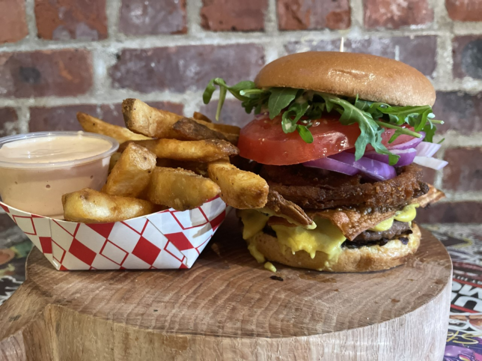 A vegan burger topped with onion rings, and fries on the side, from Bo Burger -- a pop up kitchen concept by Lucas Ortega.