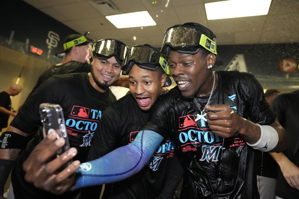 Miami Marlins' Tanner Scott, right, takes a selfie with teammates during a locker room celebration after the Marlins clinched playoff berth with a 7-3 win over the Pittsburgh Pirates in a baseball game in Pittsburgh, Saturday, Sept. 30, 2023. (AP Photo/Gene J. Puskar)