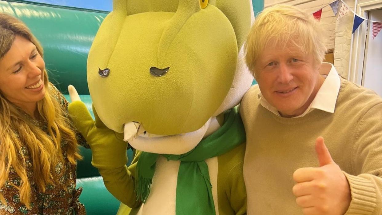 Boris and Carrie smiling with a dinosaur