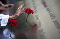 A woman touches a carnation left on a name inscribed into the North Pool during 9/11 Memorial ceremonies marking the 12th anniversary of the 9/11 attacks on the World Trade Center in New York on September 11, 2013. REUTERS/Adrees Latif