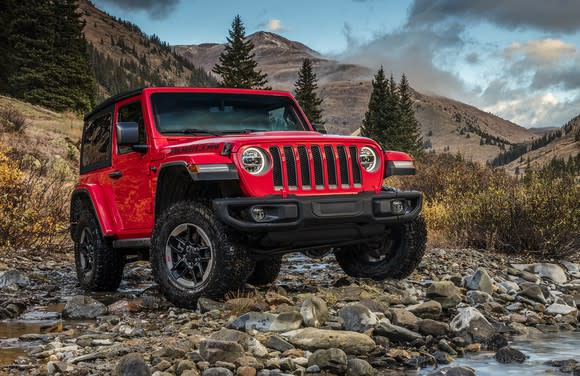 A red 2018 Jeep Wrangler, an off-road SUV, on a rocky hillside.